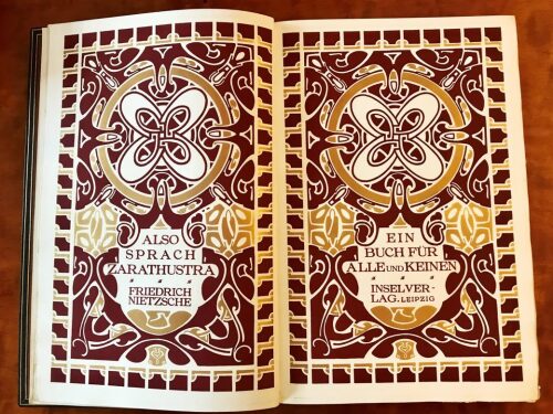 Double-page ornamental title in burgundy and gold