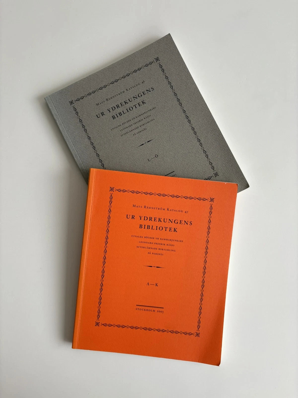 Two books, one gray and one orange, on a light gray background